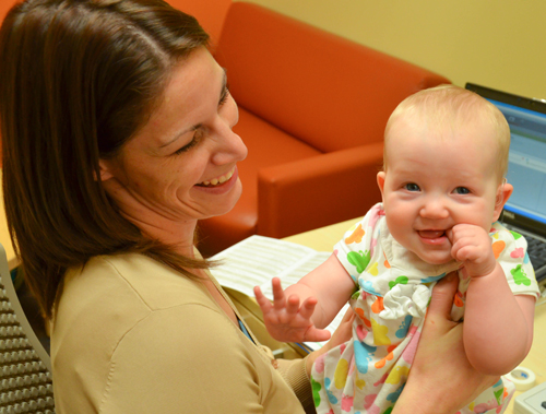 a smiling audiologist holding a smiling baby