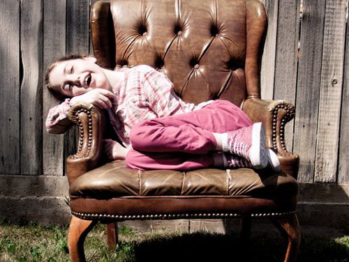a smiling girl sitting in an armchair, outside