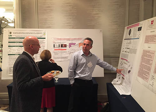 attendee listens as a presenter talks about his poster presentation